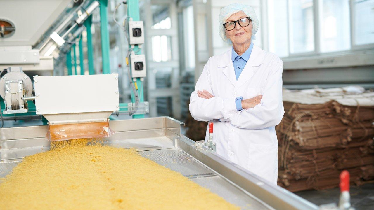 Person in einer Produktionsumgebung für geriebenen Käse Person in einer Produktionsumgebung für geriebenen Käse